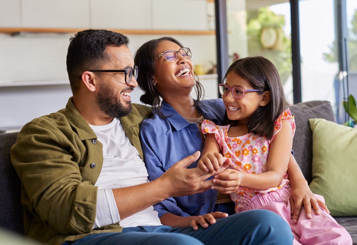 Family laughing at home sitting at a couch