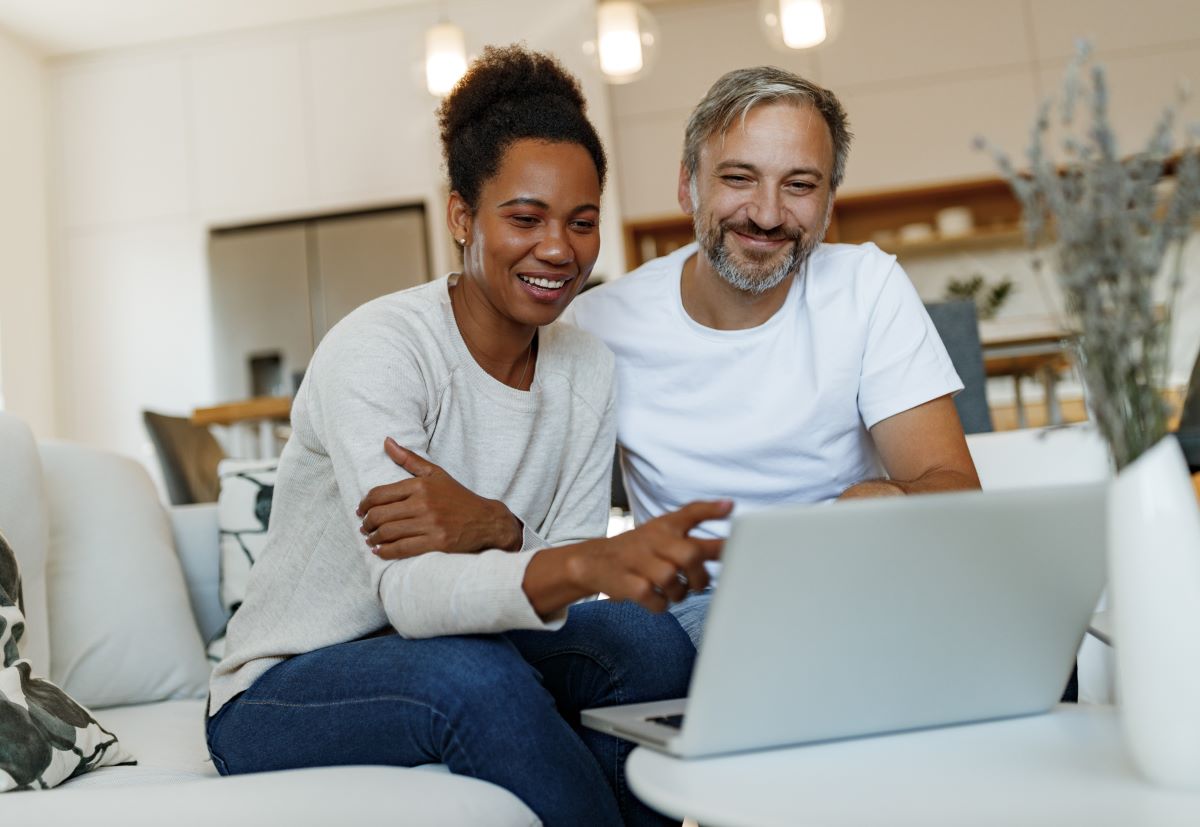 Couple looking at a laptop sitting on a couch