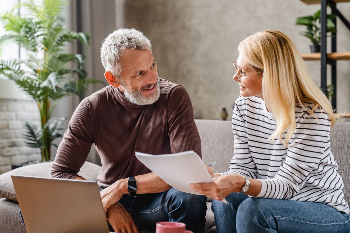 Couple talking and looking at a laptop on a couch
